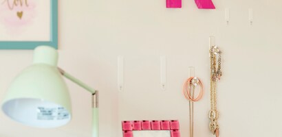 White bedroom wall with four clear Command Clear Crystal Hooks with two having necklaces hanging from them.
