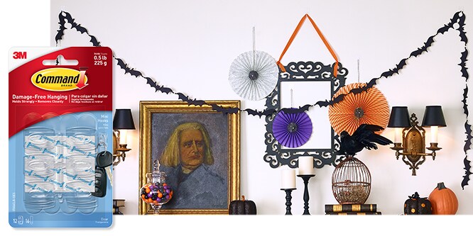 Command&amp;amp;amp;amp;amp;trade; Clear Mini Hooks used to hang up Halloween decorations of hanging paper lanterns, a bat banner, decorative mirror, and spider webs.
