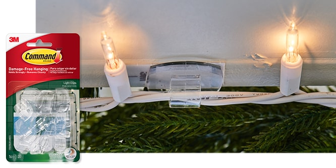 Command™ Outdoor Light Clips holding string lights in place along holiday greenery.
