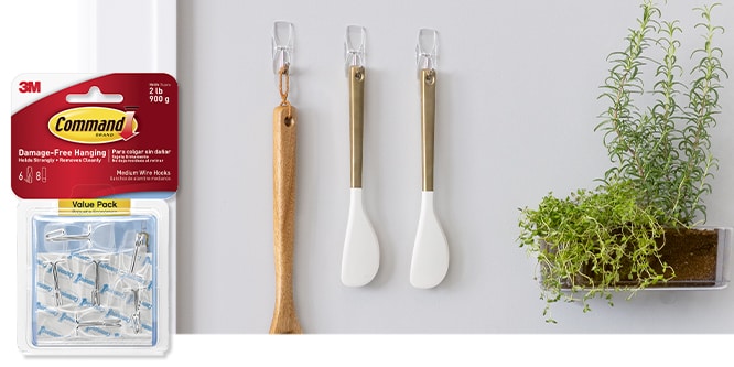 Command™ hooks holding kitchen utensils and a plant shelf; packaging of hooks shown on left.
