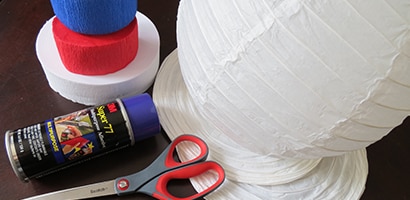 Begin by spraying red and blue crepe paper with Scotch® Super 77™ Multipurpose Spray Adhesive and then press it onto paper lanterns.
