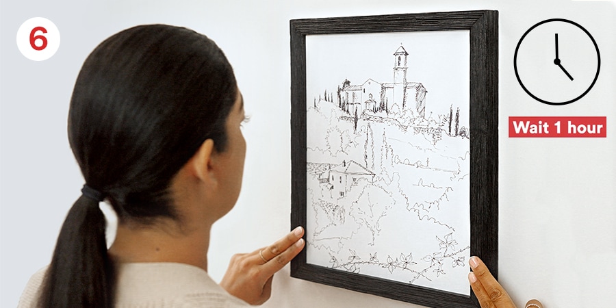Person hangs framed sketch of a landscape on a wall. Clock shows 1-hour wait.