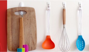 Kitchen utensils hung on a wall using white Command™ Hooks.
