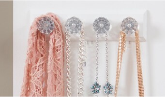 3 necklaces and scarf hung on a wall with ornate and decorative Command™ Hooks.
