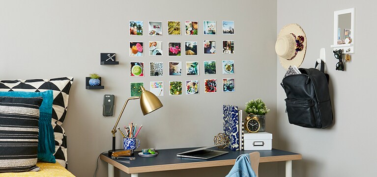 Une chambre de résidence avec un lit et un bureau. Il y a diverses photos sur le mur, ainsi que des bibelots sur les Tablettes d’appui Command(MC), un Mirroir à crochets Command(MC) et un sac accroché à un Crochet géant Command(MC).