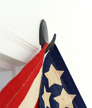 Then, remove the black “wall side” liner and press the hook onto the siding above the front door, pressing firmly along the entire hook for 30 seconds.

