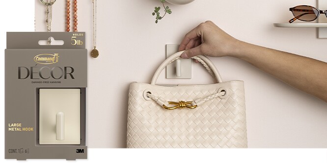 Command™ Large Metal Hook in light beige holding a purse on a white wall.
