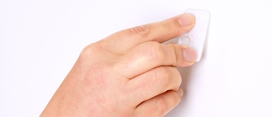 Une main qui décolle un Crochet repositionnable Adjustables(MC) Command® d’un mur.
