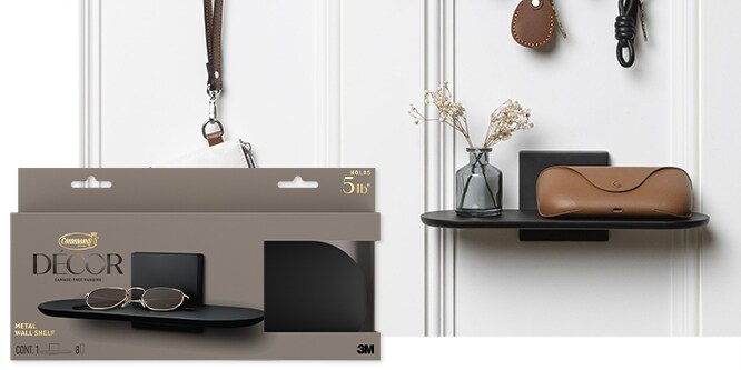 Command™ Metal Wall Shelf in matte black holding a small glass vase with dried flowers, and a sunglasses case on a white wall.
