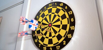 A black and yellow dart board hanging on a Command Utensil Hook.
