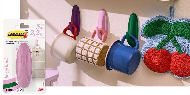 Command™ Large Hooks on a wall holding various mugs. Packaging shown on the left.
