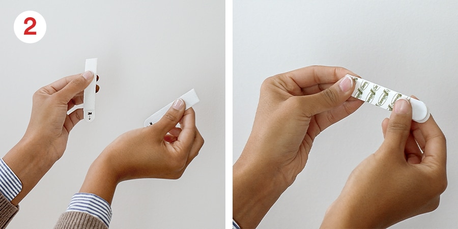 Two-panel image showing hands separating and holding a wall adhesive strip; step 2 in application process.