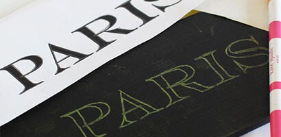 Une planche de pin peinte en noir indiquant le mot Paris, imprimé à partir d’un papier-calque.

