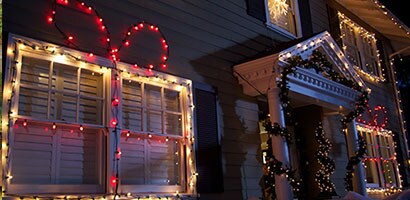 L’extérieur du devant d’une maison décorée pour Noël avec des lumières accrochées à l’aide de Pinces pour lumières Command(MC).
