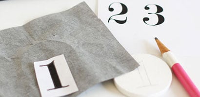 Painted white pine disc with transfer paper numbers and pencil to label key hooks. 

