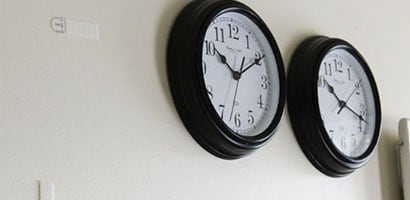 Two oval wall clocks with black borders and white faces hung on a wall.
