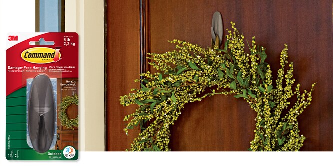 Command™ Outdoor Large Metallic Bronze Designer Hook holding a wreath on a wooden door next to its packaging.
