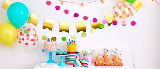 A table with a cake, party hats, goodie bags, and decorations.
