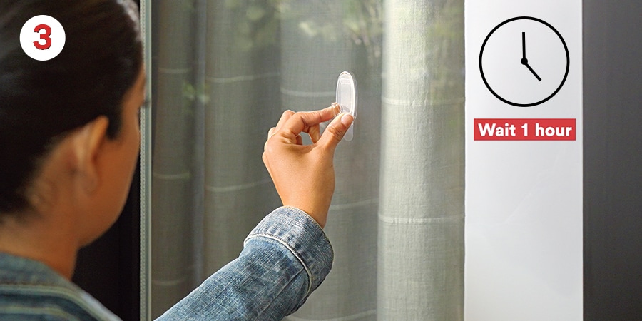 Hands pressing a hook against a window. A clock in the corner reads “Wait 1 hour” before use.