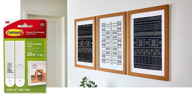 Command™ 20lb Picture Hanging Strips, behind the product in package, strips are used to hold three pictures on a wall.
