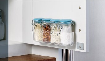 Backside of a pantry door using a Command™ Clear Caddy to organize jars of spices and seasonings.
