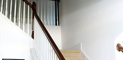 View of a staircase with empty white wall from the bottom floor.
