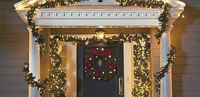 L’entrée extérieure d’une maison avec une guirlande et des lumières de Noël blanches accrochées à l’aide de Pinces pour lumières Command(MC).
