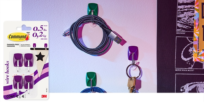 Command™ Small Wire Hooks on a wall holding cords and keys. Packaging shown on the left.
