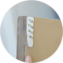 Command™ Picture Hanging Strip securely applied to the back corner of a wood picture frame.
