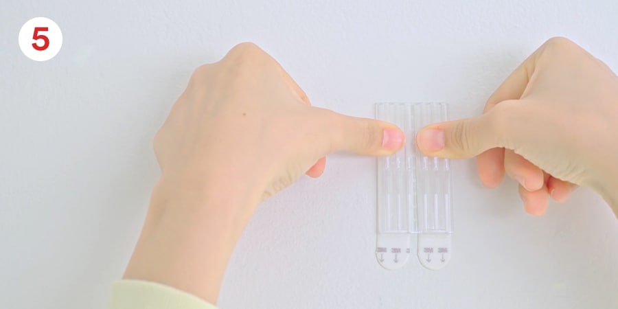 Step 5 - Hands show pressing the base to the wall.