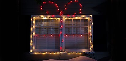 Deux panneaux de fenêtres extérieures décorés de lumières de Noël blanches et rouges à l’aide de Pinces pour lumières Command(MC).
