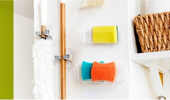 Utility closet with cleaning supplies hung using Command™  Broom & Mop Grippers and several sponge caddies.
