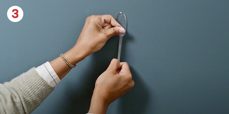 Hands stretch the strip slowly against the wall (at least 12 inches) to release.
