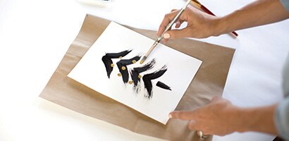 Woman painting gold balls onto the abstract Christmas tree.
