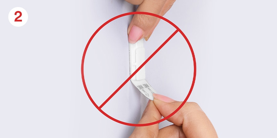 Hands pulling strip away from the wall, a red prohibited circle with a strike through it overlaps the image.