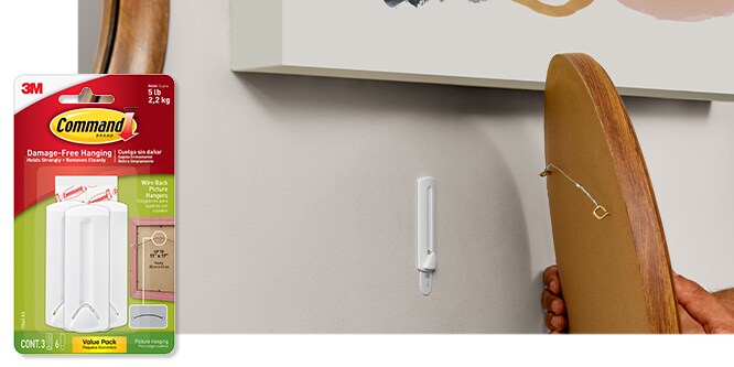 Command™ Wire Back Picture Hanger, behind the product in package, the hook is used to hold a cutting mirror on a wall.
