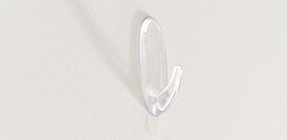 Un Crochet transparent Command(MC) appliqué sur un mur blanc.
