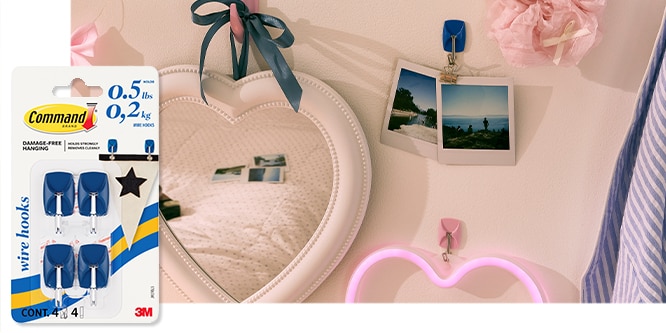 Command™ Small Wire Hooks shown in use, holding photos on a decorative wall with a heart-shaped mirror and neon light.
