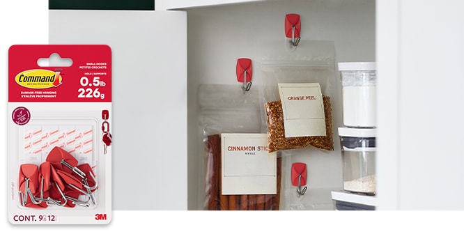 Command™ Small Wire Hooks on the inside of a cabinet holding bags of spices.

