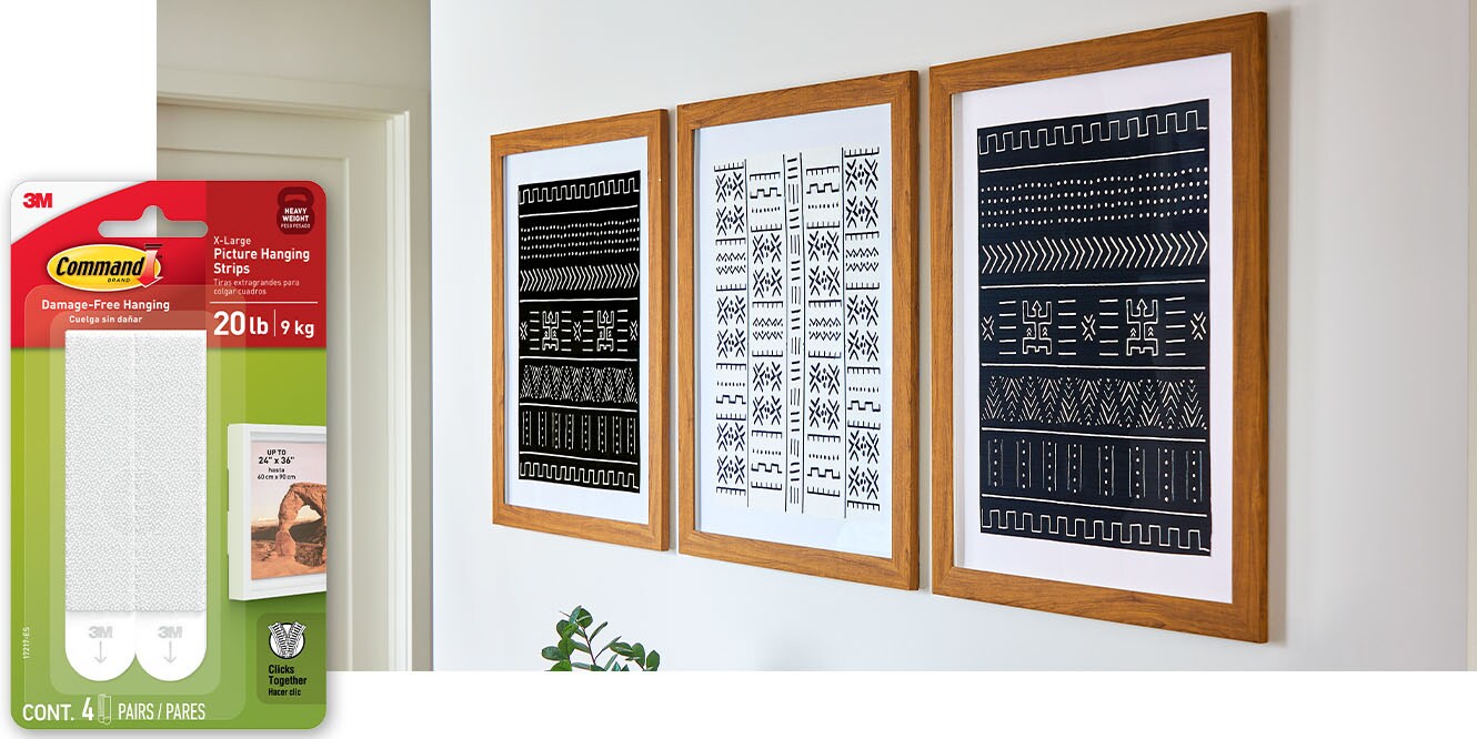 Command™ 20 lb Picture Hanging Strips holding three framed art pieces on the wall.
