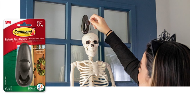 Command&amp;amp;amp;amp;amp;amp;amp;amp;amp;trade; Outdoor Large Oil Rubbed Bronze Hook holding up a Halloween skeleton on a front door.
