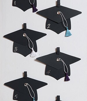 5 completed graduation hats hanging on Command Slate Spring Clips.

