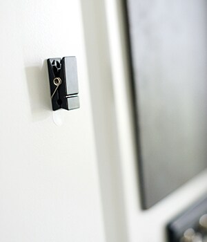 To hang the Command™ Slate Spring Clips below the key rail, first remove the clips and adhesive strips from the packaging, and separate the strips from one another

