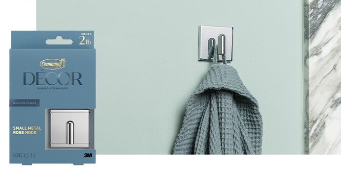 Command™ Small Metal Robe hook in chrome holding a green robe on a mint green wall.
