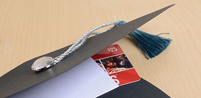 mortarboard cutout lifted up to reveal an envelope with a gift card underneath.
