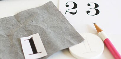 Disque de pin peint en blanc avec des numéros de papier-calque et un crayon pour étiqueter les crochets pour clés. 
